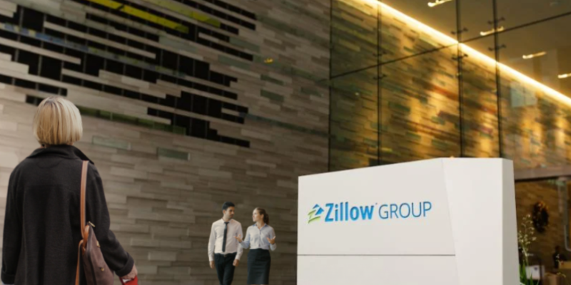 People walking into and out of a Zillow Group office with Zillow sign in front.